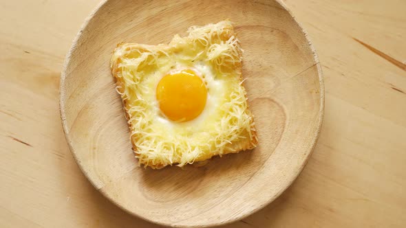 Top View of Toast with Fried Egg and Cheese on Wooden Kitchen Table