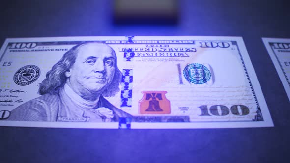 American dollars checked by the UV light detector. Searching for fake money. 4K