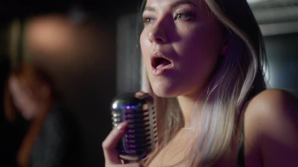 Closeup Portrait of Confident Artistic Talented Beautiful Woman Singing with Microphone in Night