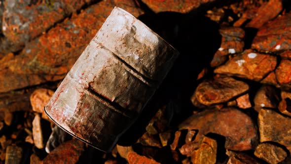 Rusty Destroyed Metal Barrel on Beach Rocks