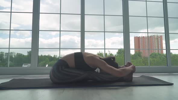 Young Female Doing Yoga in a White Room Girl Performs Muscle Stretching Near the Large Window