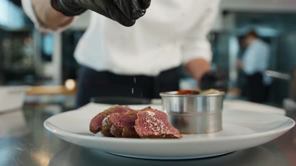 The chef sprinkles the filet mignon with coarse salt. Serving food in a restaurant.