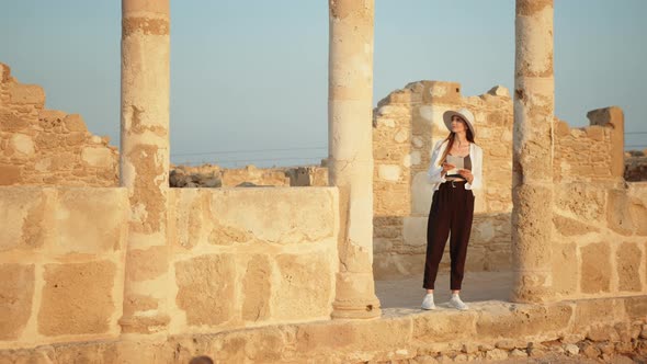 Girl Tourist In an Ancient Temple with Columns Looking at Records of a Map