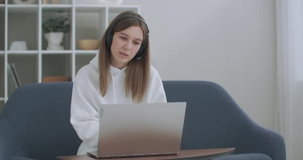 Young Woman Wears Headset Conference Calling on Laptop Talks with Online Teacher Studying, Working