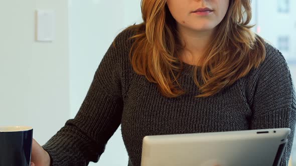 Woman using digital tablet while having coffee