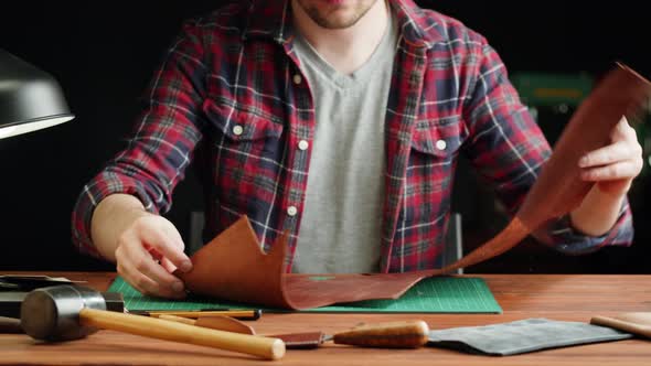 Man Tailor Cutting Artificial Leather with Stencil Closeup