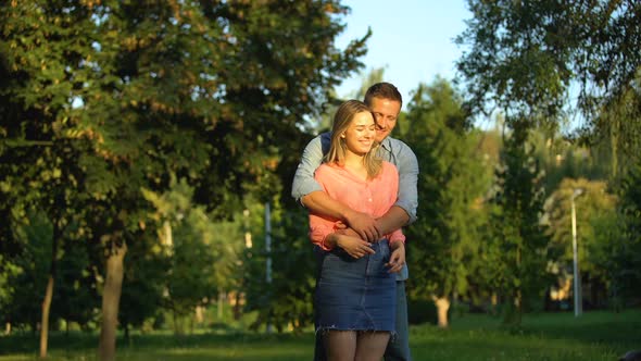 Cheerful Couple Cuddling at Park, Enjoying Time Together, Trustful Relations