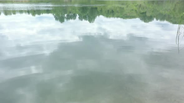 Reflection of cloudy sky on pond water surface 4K drone video