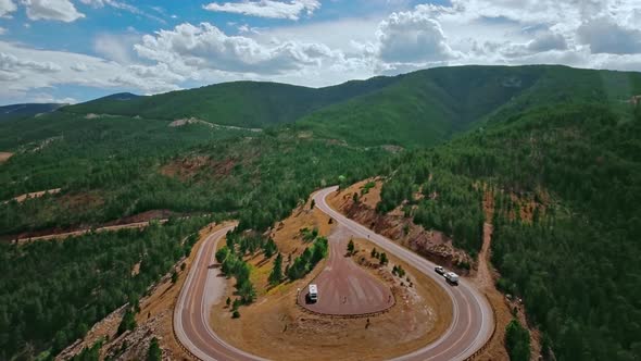 Drone filming a winding road on a mountainside that wriggle through a dense forest in Wyoming, USA