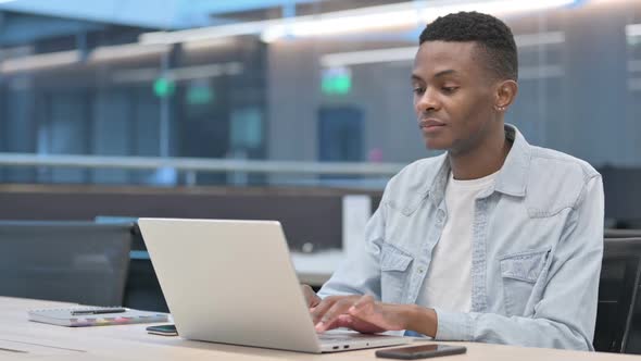 African Man with Laptop Smiling at Camera