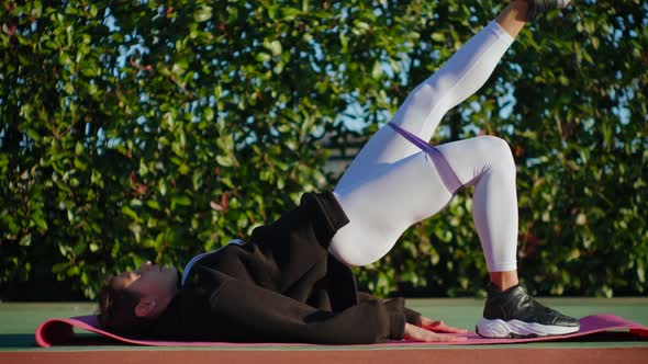 Fitness Trainer with a Rubber Sports Belt Training Her Buttocks