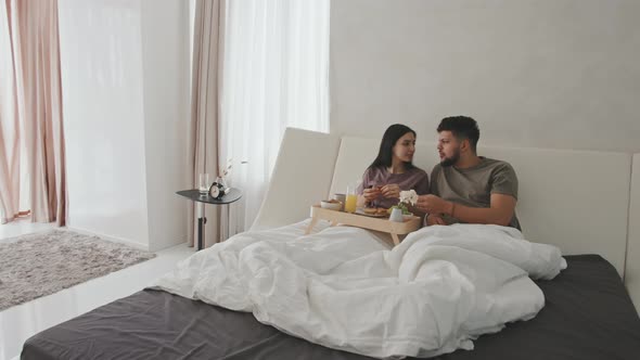 Latin Couple Chatting During Breakfast In Bed