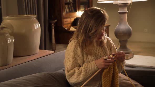 Young woman knitting at home