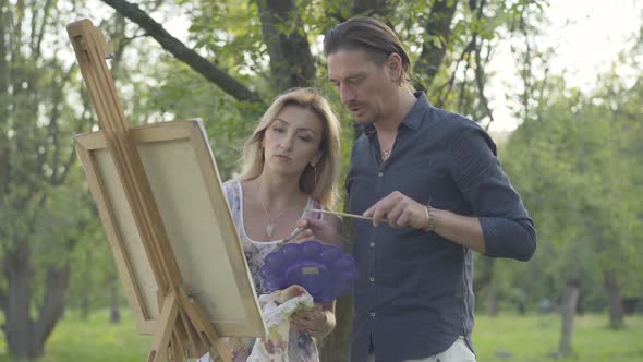 Confident Brunette Man and Blond Woman Creating Artwork in Sunny Summer Park. Portrait of Caucasian