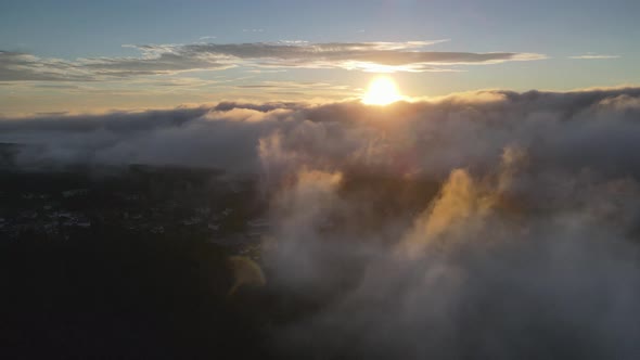 Drone flying over clouds at sunrise and Caramulo city in background, Portugal
