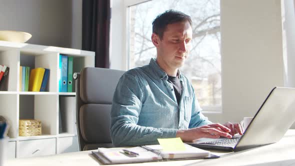 Young male entrepreneur works at home office at the computer.