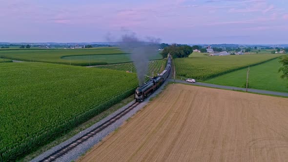 Aerial View of a Steam Train Approaching Flying Ahead Traveling Thru Farmlands and Corn Fields