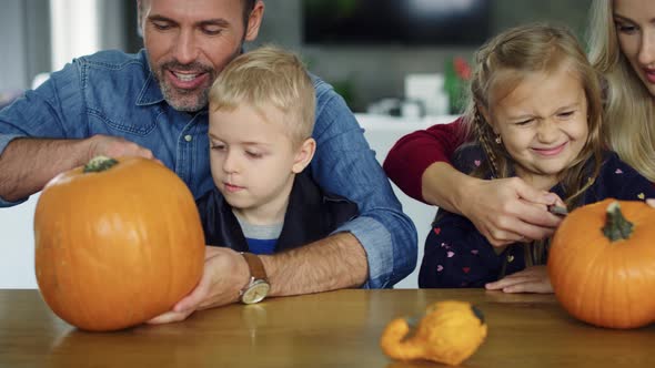 Parents helping children in carving pumpkins