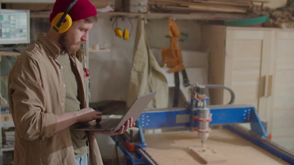 Carpenter Working with Laptop in Woodworking Workshop