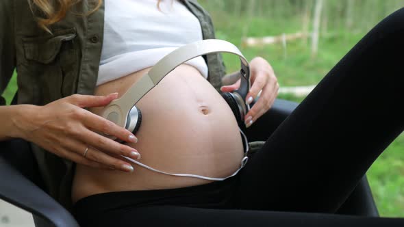 close-up of a pregnant woman with headphones on her stomach