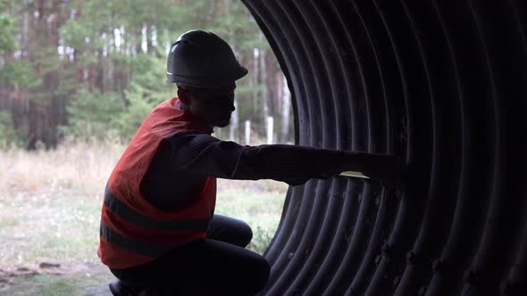 A builder engineer makes measurements of the structure of an underpass under the railway.