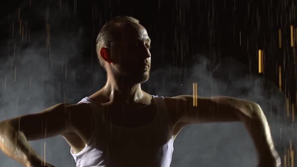 Male Dancer Dancing Elements of Salsa in the Pouring Rain in a Dark Smoky Studio. A Silhouette of a