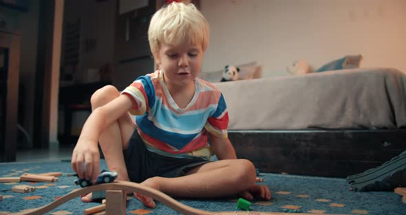 Cute Happy Boy Playing Wooden Railway Road Toy in Living Room on Evening