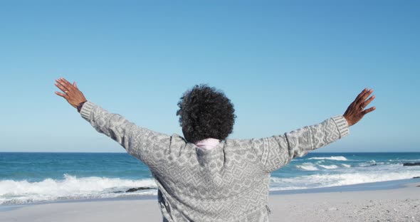 Senior woman raising her arms at the beach