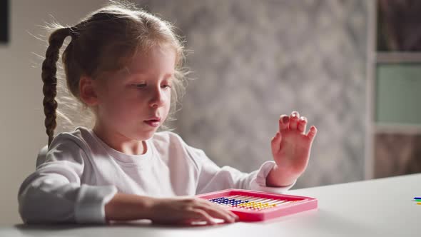 Inspired Little Girl Learn to Count with Toy Abacus at Desk