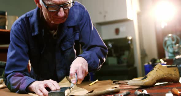 Shoemaker cutting a piece of leather