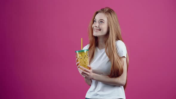 The Redhaired Student Satisfied with a Glass of Juice in Her Hand Smiles Dreamily