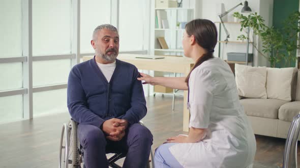 A Middleaged Man in a Wheelchair Talking to a Nurse