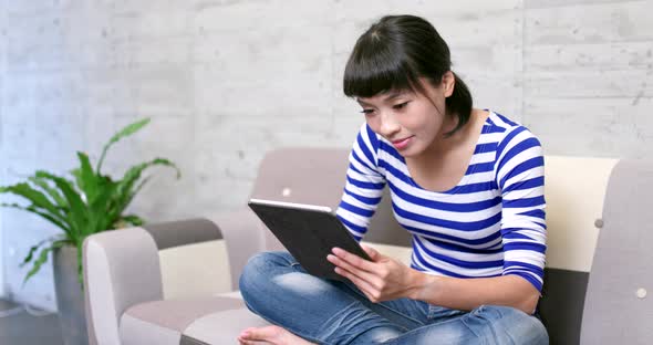 Woman watching on tablet computer at home