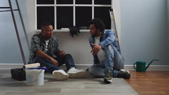 Tired AfricanAmerican Guys Talk Sitting on Floor at Window