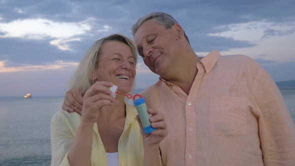 Senior couple blowing bubbles at the seaside