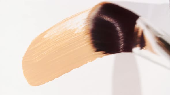 Macro Shot and Slow Motion of a Brush Applicator Smear Concealer Isolated on White Background