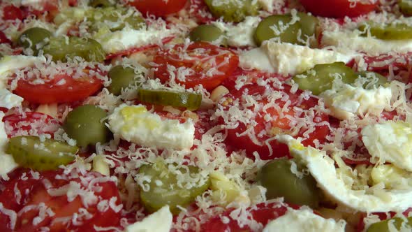 Spinning pizza with mozzarella cheese, olives, pickled cucumbers, tomatoes, parmesan cheese