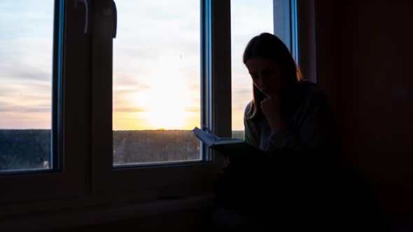 Timelapse of a Lonely Girl Reading a Book Against the Backdrop of Orange Sunset