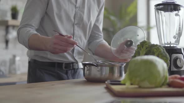 Handsome Skill Smilling Man in the Shirt Cooking Soup in the Kitchen