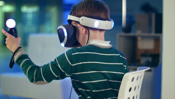 Little Boy with Virtual Reality Motion Controllers Having Immersive Gaming Experience