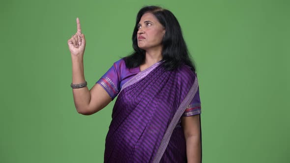 Mature Beautiful Indian Woman Pointing Up While Thinking