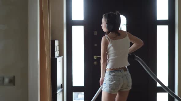 A girl in a good mood dancing and vacuuming at home