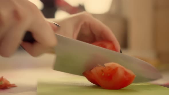 Woman cuts ripe tomato with sharp knife