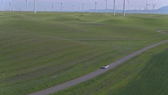 Car Driving On The Dirt Road Among Windmills