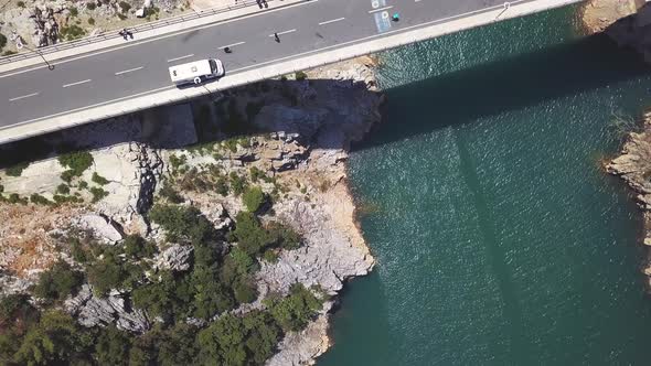 Aerial top view of a bridge crossing the blue sea and rocks