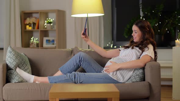 Happy Pregnant Woman with Tablet Pc at Home