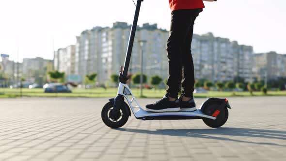 Deliverman Courier With Isothermal Backpack Rides His Electric Scooter Along Wall in Urban Style