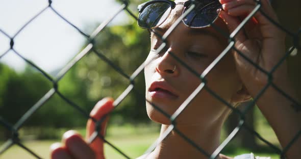 Mixed race woman looking through a fence