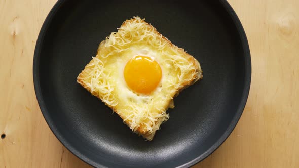 Top View of Toast with Fried Egg in Pan on Wooden Kitchen Table