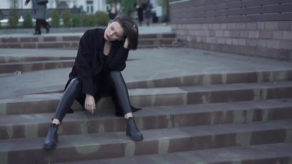 Lady in Black Poses with Her Hairstyle on Street Stairs at Camera